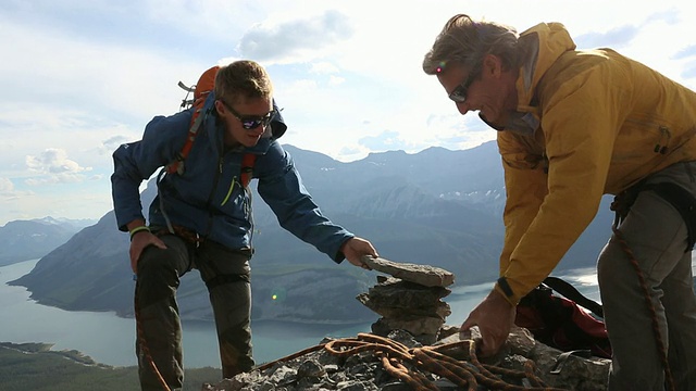 登山者们一起在mtn山顶建造石堆视频素材