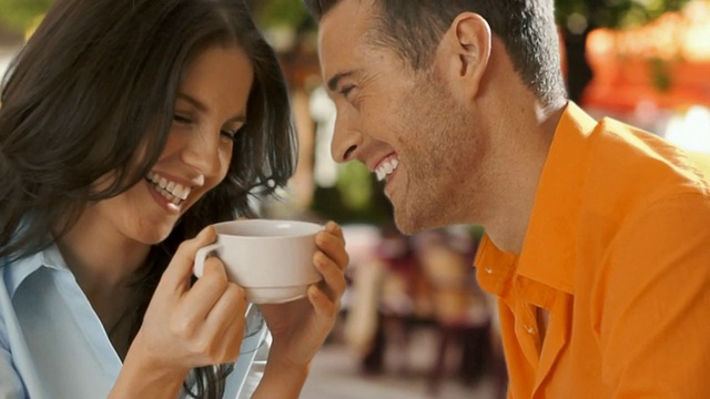 一对年轻夫妇坐在咖啡馆里一起大笑。视频下载