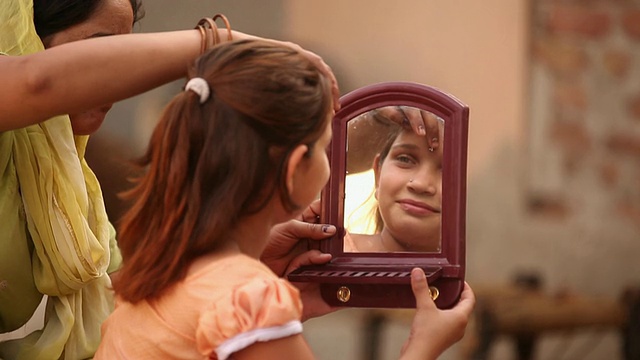 印度哈里亚纳邦，法里达巴德，一名妇女在女儿额头上涂上了“宾迪”视频素材