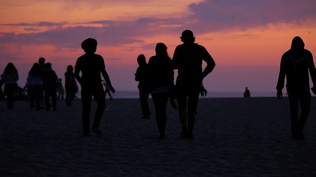 黄昏时在海滩上散步的人们视频素材