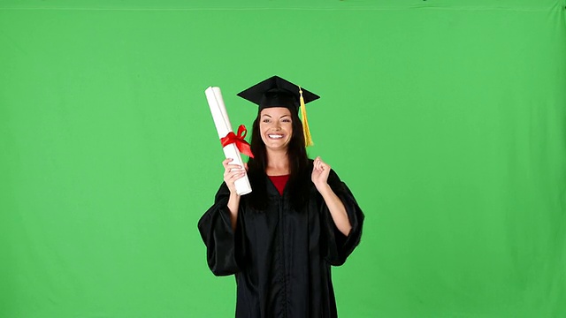 年轻激动的女人毕业在长袍与文凭视频素材