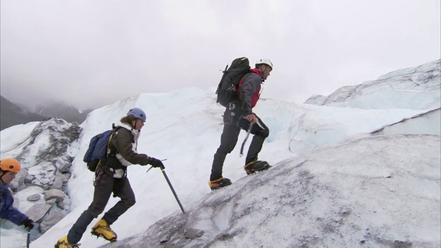 “低角度右轨迹”——登山者在朱诺冰原(Juneau Ice Fields)的一座冰川上徒步行走。/阿拉斯加,美国的视频素材