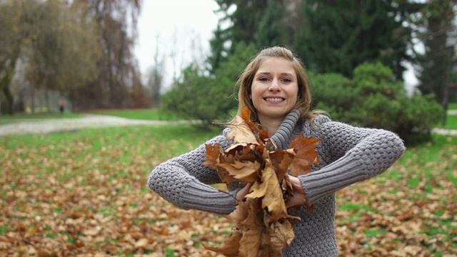 女孩微笑着把秋叶扔向镜头视频素材