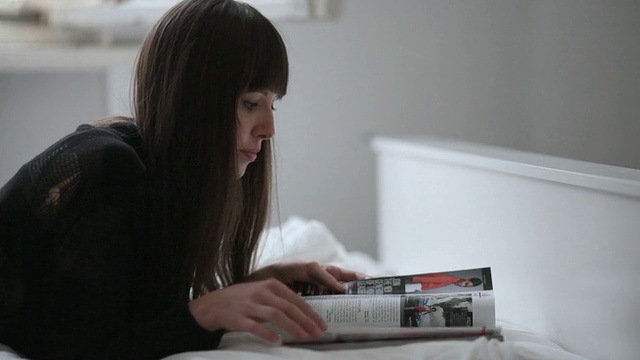 德国柏林，一名年轻女子躺在打开的窗户旁看杂志视频下载