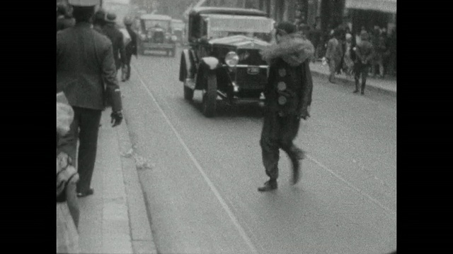 1927年，布宜诺斯艾利斯狂欢节上，一名打扮成小丑的男子经过一辆老爷车。视频素材