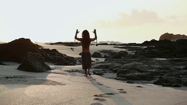 哥斯达黎加，Punteranes, Montezuma, TU Rasta man在日出的海滩上举起他的手举着poi球视频素材