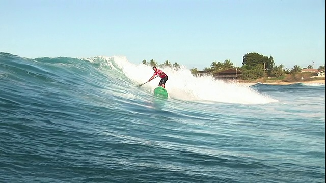 长镜头手持右跟踪-一个冲浪者在握着桨的时候擦身而过。美国夏威夷/视频下载