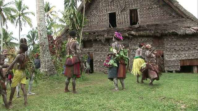 长镜头手持式-原住民穿着传统服装在长屋外跳舞。/巴布亚新几内亚视频下载