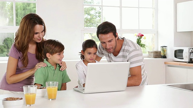 一家人在厨房里使用一台白色笔记本电脑视频素材