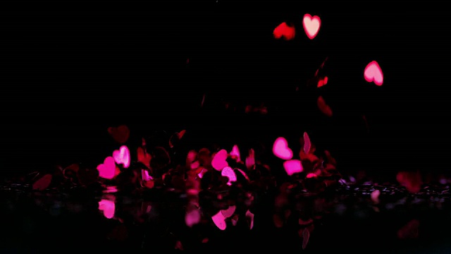 粉红色的心形纸屑落在黑色的背景上视频素材