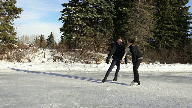 冬天，一对年轻的情侣在冰上滑冰视频素材