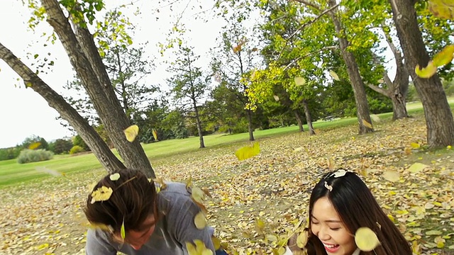 年轻的夫妇在秋天的树叶视频素材
