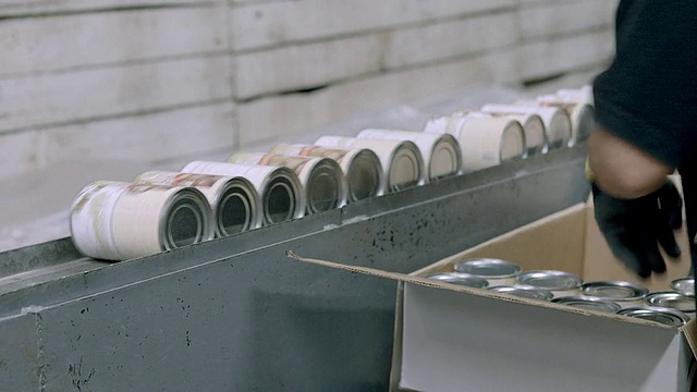 工人们从罐头贴标机的出口斜槽中挑选新贴上标签的橄榄罐头，并将罐头放入纸箱中，以便运输/美国加利福尼亚州的安大略省视频下载