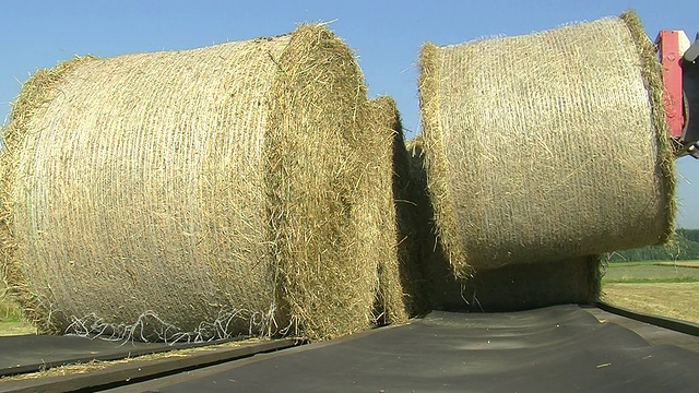 CU拖拉机在德国莱茵兰-普法尔茨萨尔堡的田里装载成捆的稻草视频下载