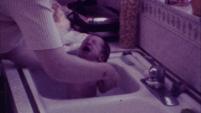 70年代的8毫米镜头，婴儿在洗澡时哭泣视频素材