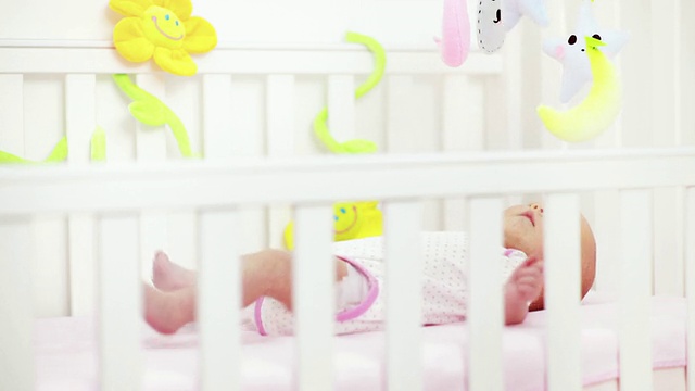 刚出生的小女孩在婴儿床里玩玩具视频下载