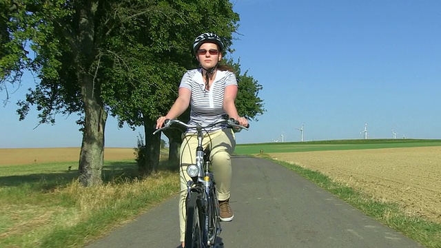 德国萨尔州，一名女子骑着自行车和头盔穿过农场视频下载