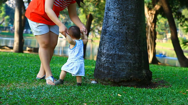 亚洲妈妈在公园里帮宝宝走路。视频素材