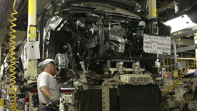 美国印第安纳州普林斯顿汽车装配厂，两名工人在小型货车底盘上安装发动机视频下载