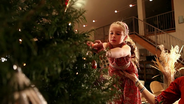 小女孩在圣诞树上挂圣诞装饰品的照片/美国新墨西哥州拉米视频素材