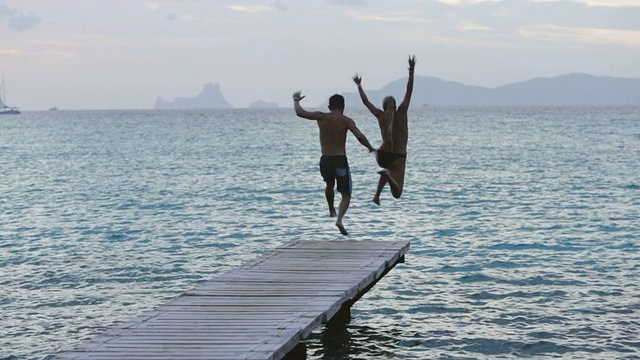 一对夫妇跑下码头，跳进了西班牙伊比沙岛的海里视频下载