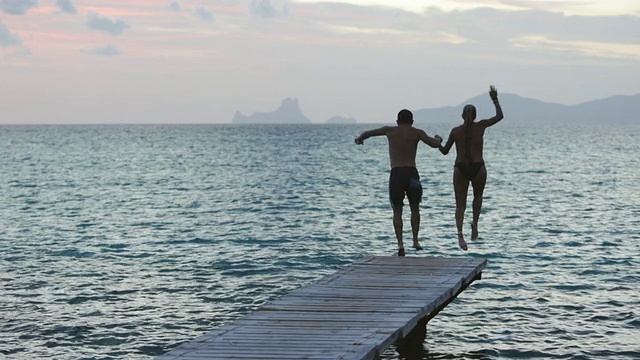 一对夫妇手牵着手走下码头，跳入大海，西班牙伊比沙岛视频下载