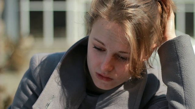 年轻女子独自坐在户外，感觉很难过，受伤，哭泣视频素材