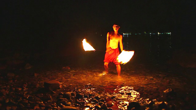 一个年轻人在海滩上表演火表演。视频素材