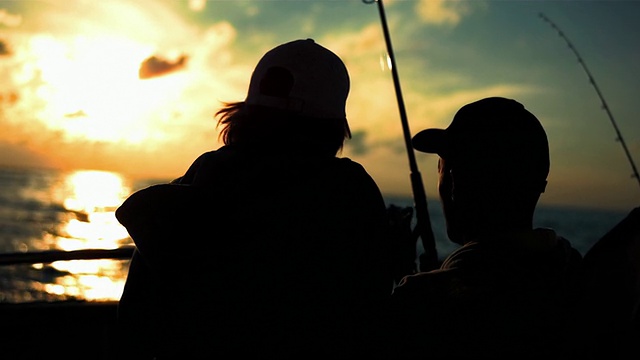 日落时分，父子俩在船上钓鱼视频素材