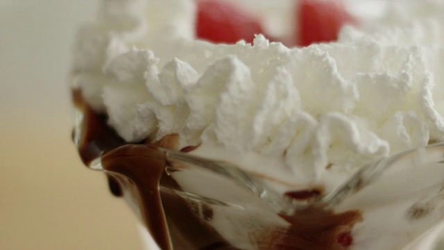 用平底锅将鲜奶油洒在冰淇淋圣代上，并将草莓片放入冻糕玻璃杯中视频下载