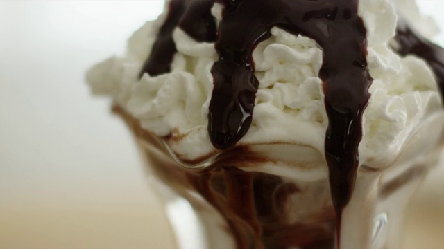 巧克力糖浆浇在生奶油上，冰淇淋圣代沿边往下滴视频下载