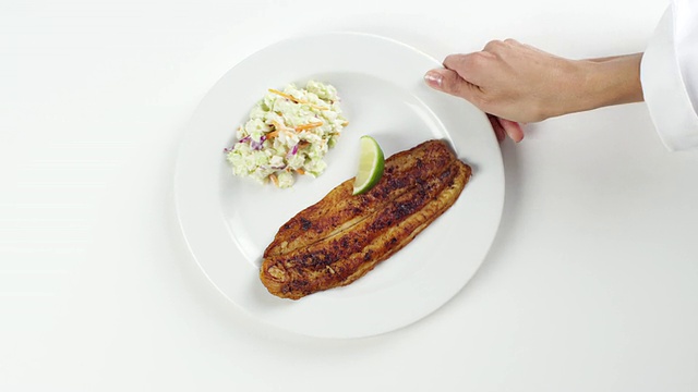美国内布拉斯加州奥马哈市，一名妇女走进餐厅，摆上一个白色盘子，上面放着黑比目鱼和卷心菜沙拉视频素材