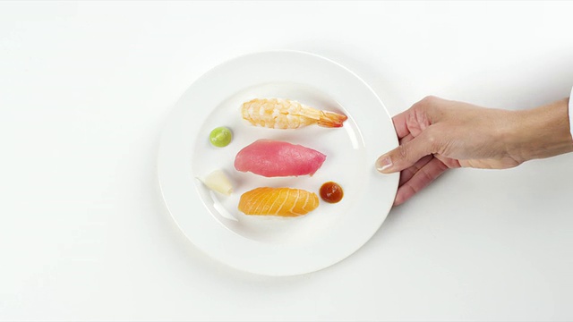 美国内布拉斯加州奥马哈市，一名妇女手持白色的盘子，上面放着五颜六色的寿司生鱼和黄尾鲑鱼视频素材