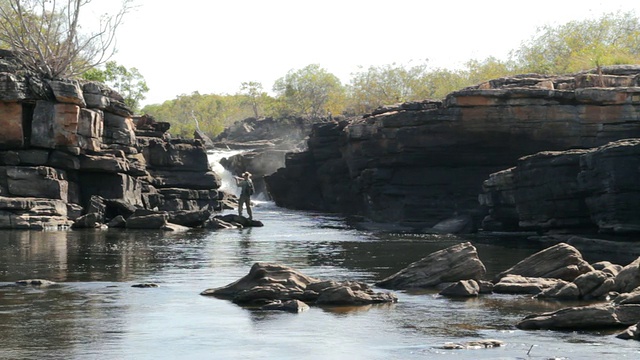 澳大利亚北部河流的小瀑布上垂钓的人视频下载