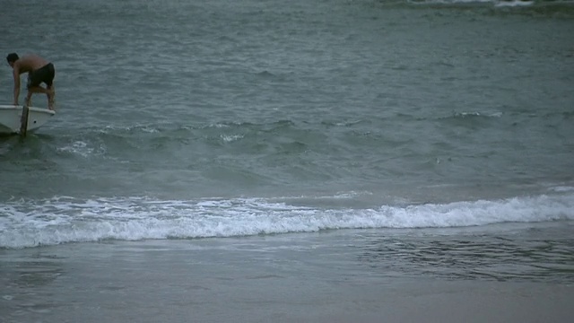 两个年轻人把小船从海滩推到海里，伊帕内玛海滩，巴西，里约热内卢[巴西]视频素材