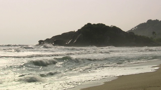 哥伦比亚内华达山脉的泰罗纳国家自然公园(泰罗纳国家自然公园)的海岸线上，汹涌的海浪拍打着沙滩上的岩石前站视频素材
