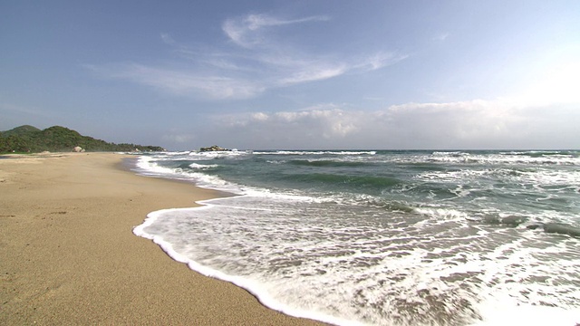 海浪拍打着沙滩，蓝天和森林覆盖的山丘，泰罗纳国家自然公园的海岸线。内华达山脉、哥伦比亚视频下载