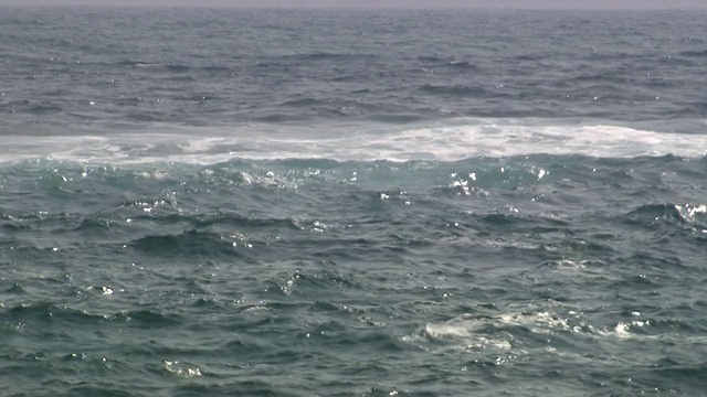 一艘载有3名男性乘客的小渔船从右到右航行在波涛汹涌的蓝色海洋上，泰罗那国家自然公园。内华达山脉、哥伦比亚视频下载