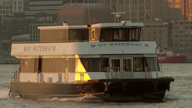 日落时分，一艘纽约水路渡船在穿过哈德逊河后减速。温暖的光线反射在小船上。视频下载