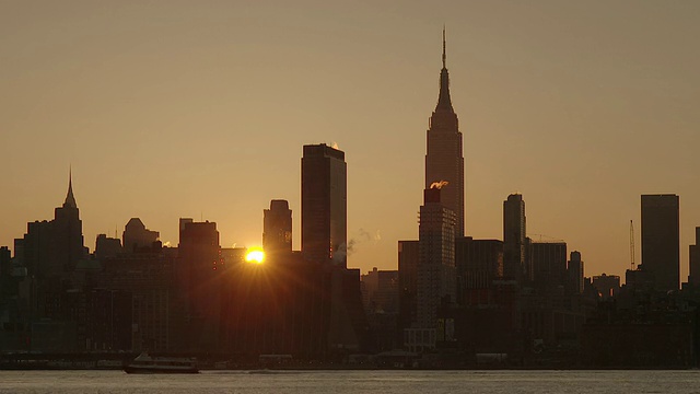 在哈德逊河上的清晨，太阳从曼哈顿中城的建筑物中升起的实时镜头。视频素材