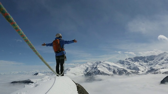 登山者张开双臂接近冰雪覆盖的山顶视频素材
