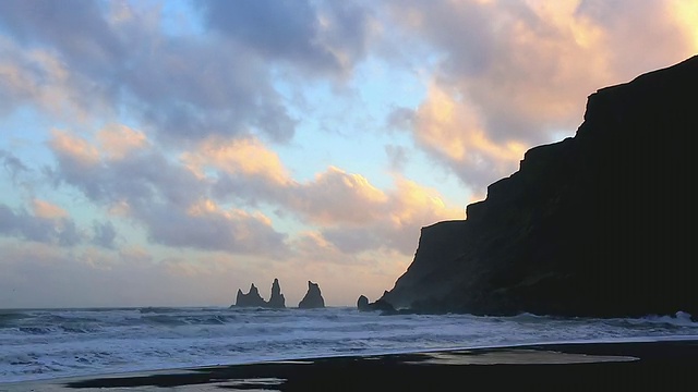 黄昏时分，海浪翻滚到维克黑沙滩，手指岩在后面/冰岛视频素材