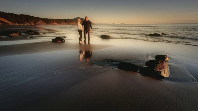 美国俄勒冈州奥福德港，一对老年夫妇在日落海滩上散步视频素材