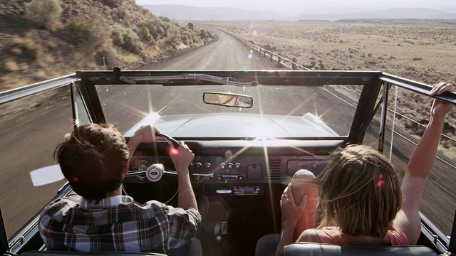 男子微笑着驾驶敞篷越野车在农村沙漠道路上女子坐在乘客座位上视频下载