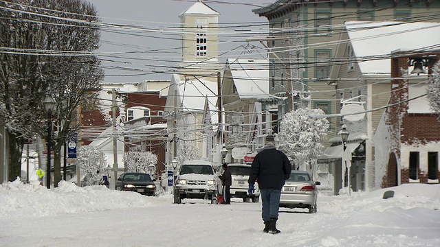 一场暴风雪后的小镇街景与汽车和行人视频素材