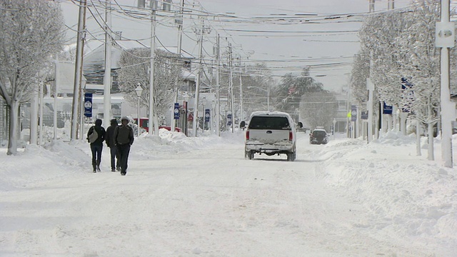 暴风雪过后，在下雪的城市街道上，路过的摄像头和几个行人视频素材
