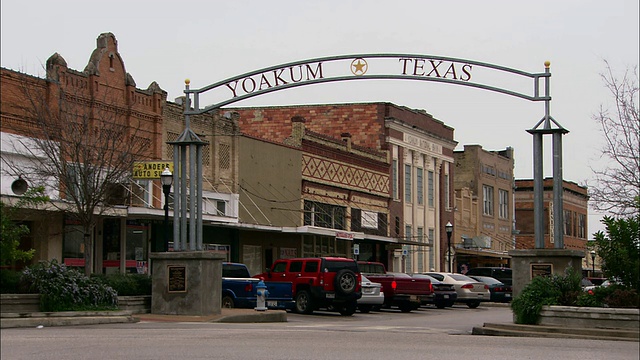 广角泛右放大——一个标志延伸在一条老式的主要街道上。/美国德克萨斯州约库姆视频素材