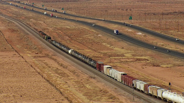 行车鸟瞰图与火车通过平行的高速公路通过沙漠/亚利桑那州，美国视频下载