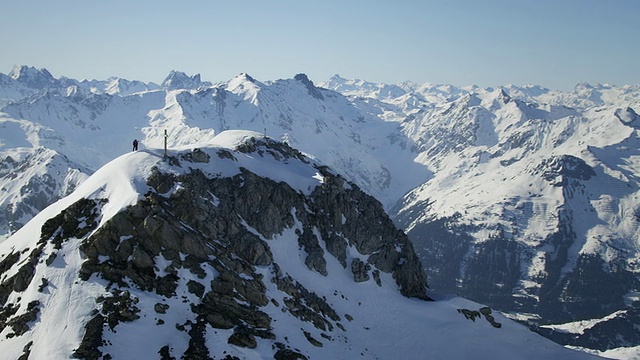 登山者在白雪覆盖的山顶上兴高采烈，山顶上有一个十字架视频素材