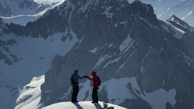 登山者在白雪覆盖的山峰上握手视频素材